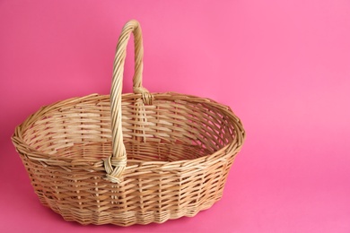 Photo of Empty wicker basket on pink background, space for text. Easter item