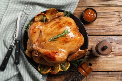 Photo of Tasty roasted chicken with rosemary and lemon served on wooden table, flat lay