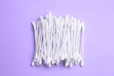 Photo of Heap of cotton buds on violet background, top view