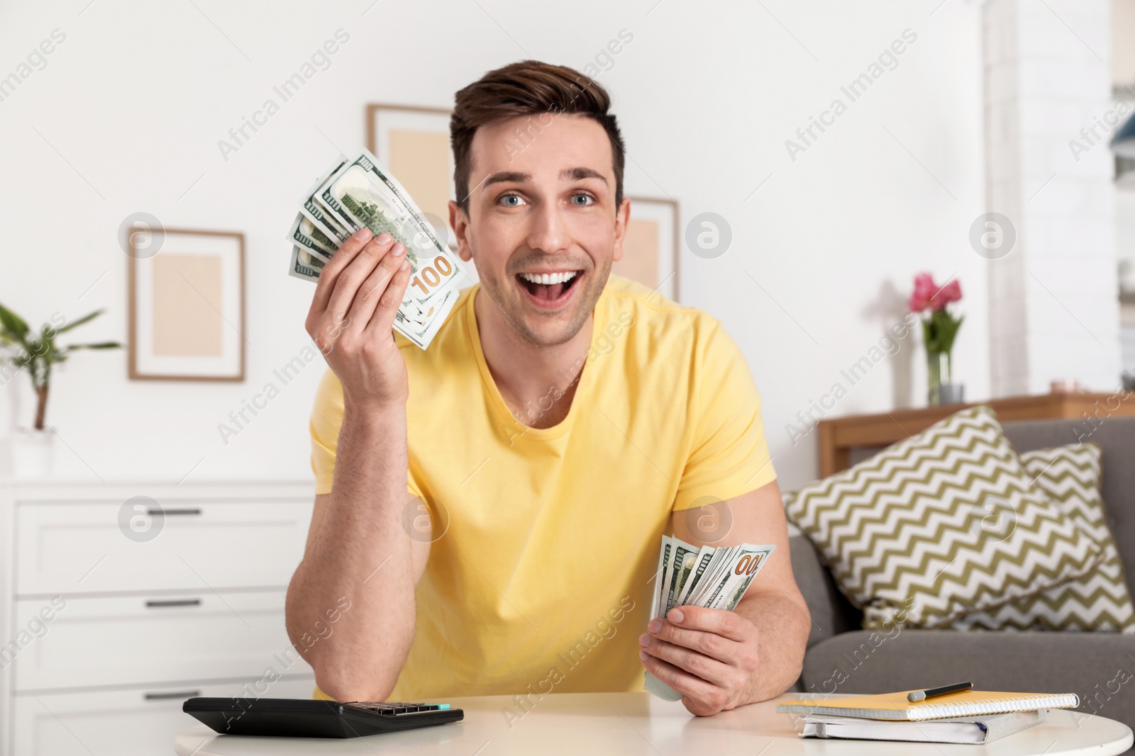 Photo of Happy man with money at table in living room