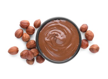 Photo of Bowl with delicious chocolate paste and hazelnuts on white background, top view