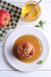 Tasty baked apple with nuts, honey and mint on white wooden table, flat lay