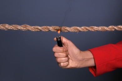 Photo of Woman scorching frayed rope on dark background