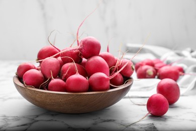 Photo of Bowl with fresh ripe radishes on white marble table, closeup