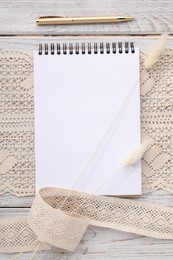 Photo of Guest list. Notebook, pen, spikelets and lace ribbons on wooden background, flat lay