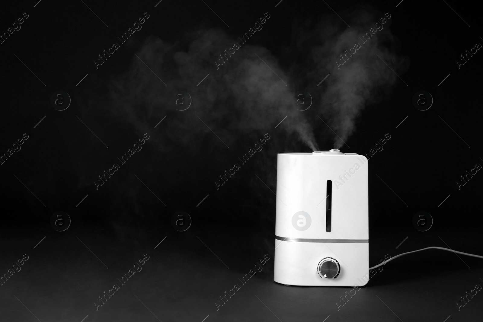 Photo of Modern air humidifier on black background. Space for text