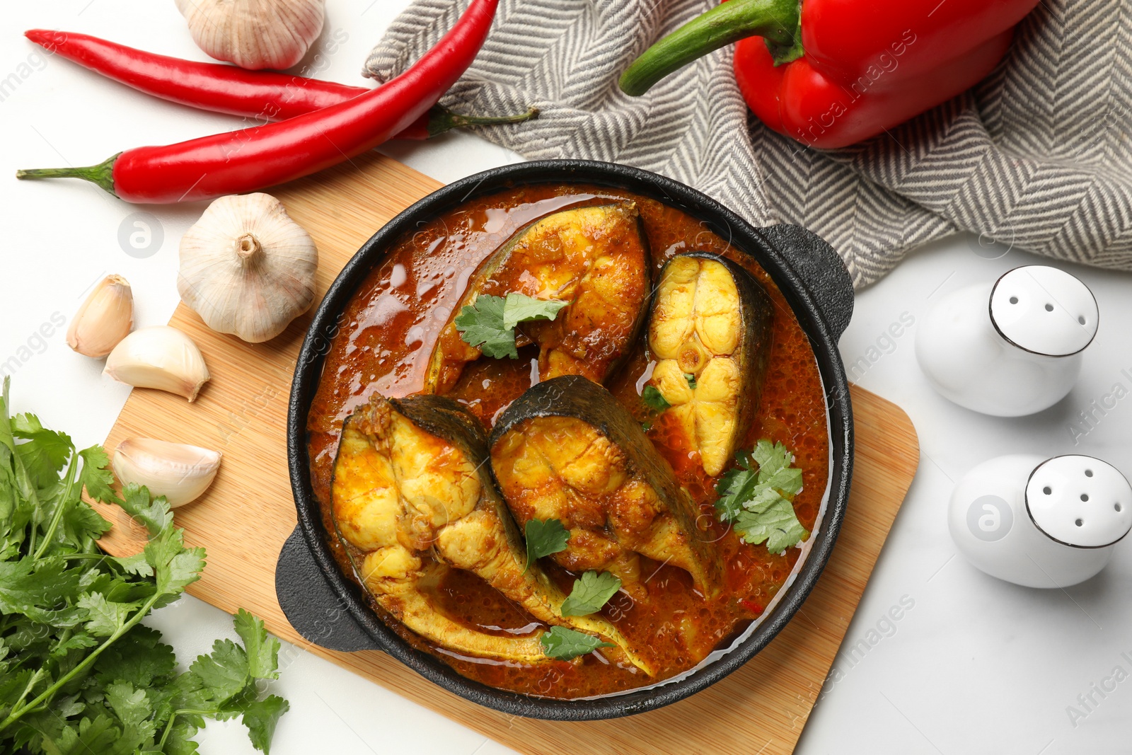 Photo of Tasty fish curry and ingredients on white table, flat lay. Indian cuisine