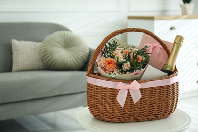 Wicker basket with gifts on table indoors. Space for text