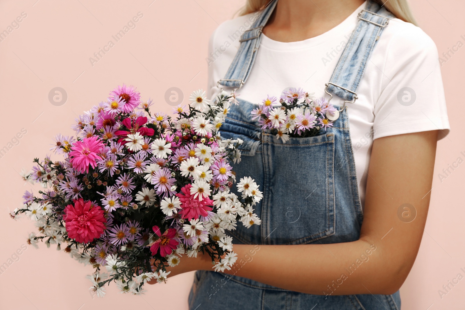 Photo of Woman with beautiful flowers on pink background, closeup