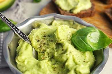 Photo of Bowl with guacamole made of ripe avocados on table, closeup