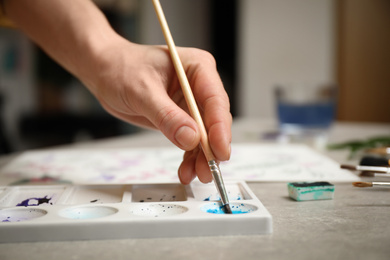 Woman painting with watercolor at grey stone table, closeup