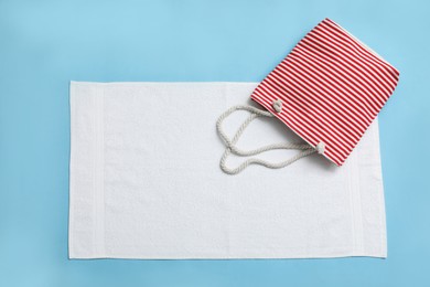 Photo of White towel and beach bag on light blue background, top view