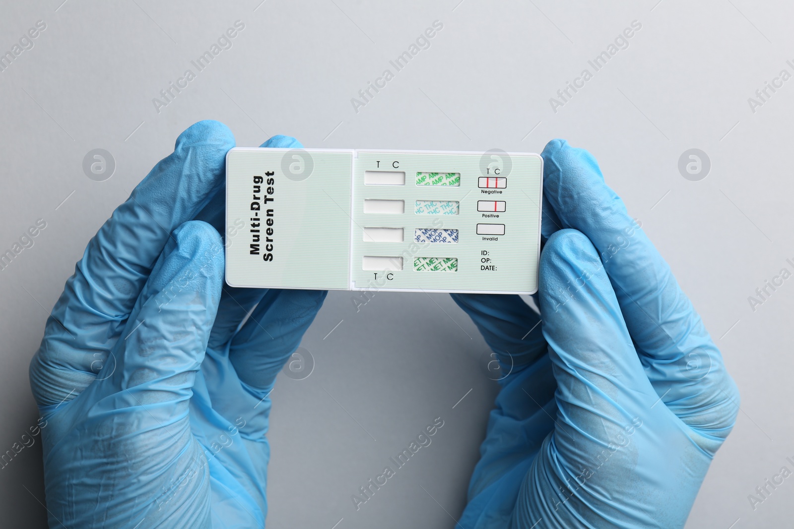 Photo of Doctor holding multi-drug screen test on light grey background, top view