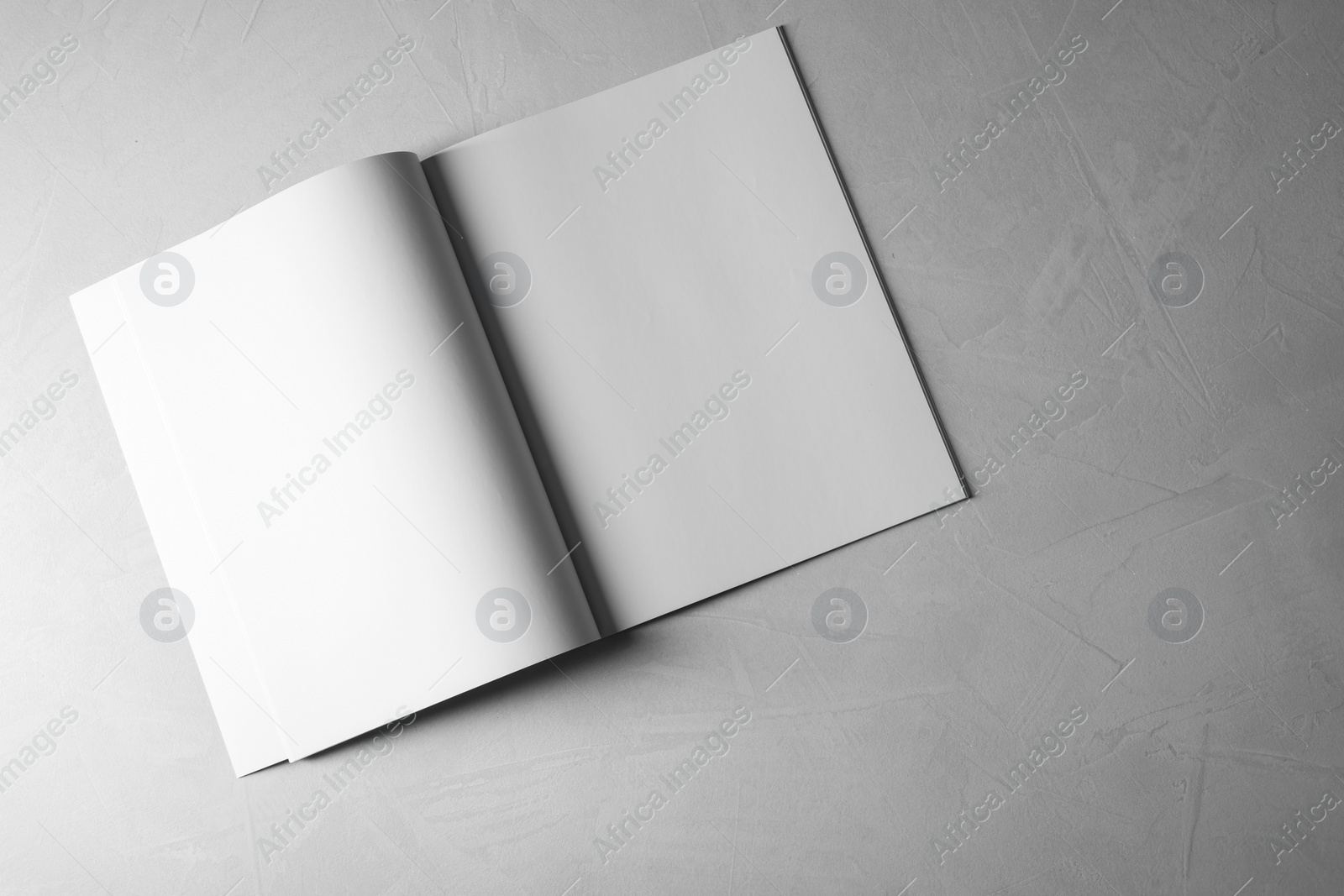 Photo of Open notebook with blank paper sheets on grey textured background, top view. Mockup for design