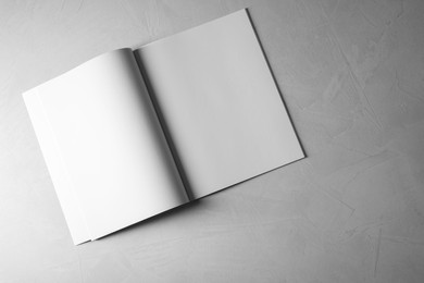Open notebook with blank paper sheets on grey textured background, top view. Mockup for design
