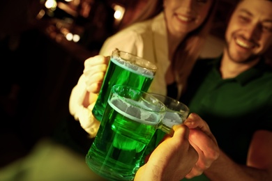 Photo of People with beer celebrating St Patrick's day in pub, focus on hands