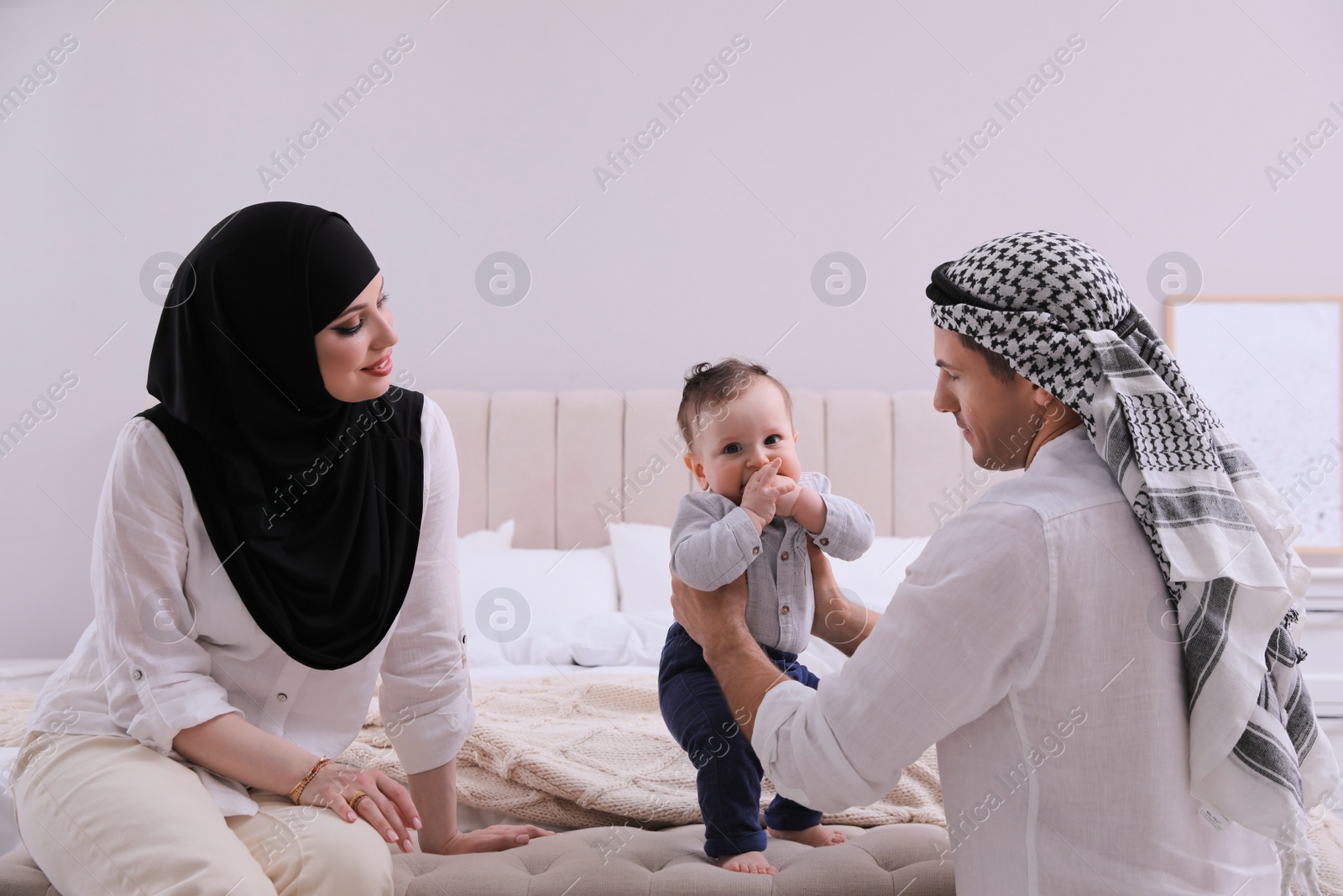 Photo of Happy Muslim family with little son in bedroom