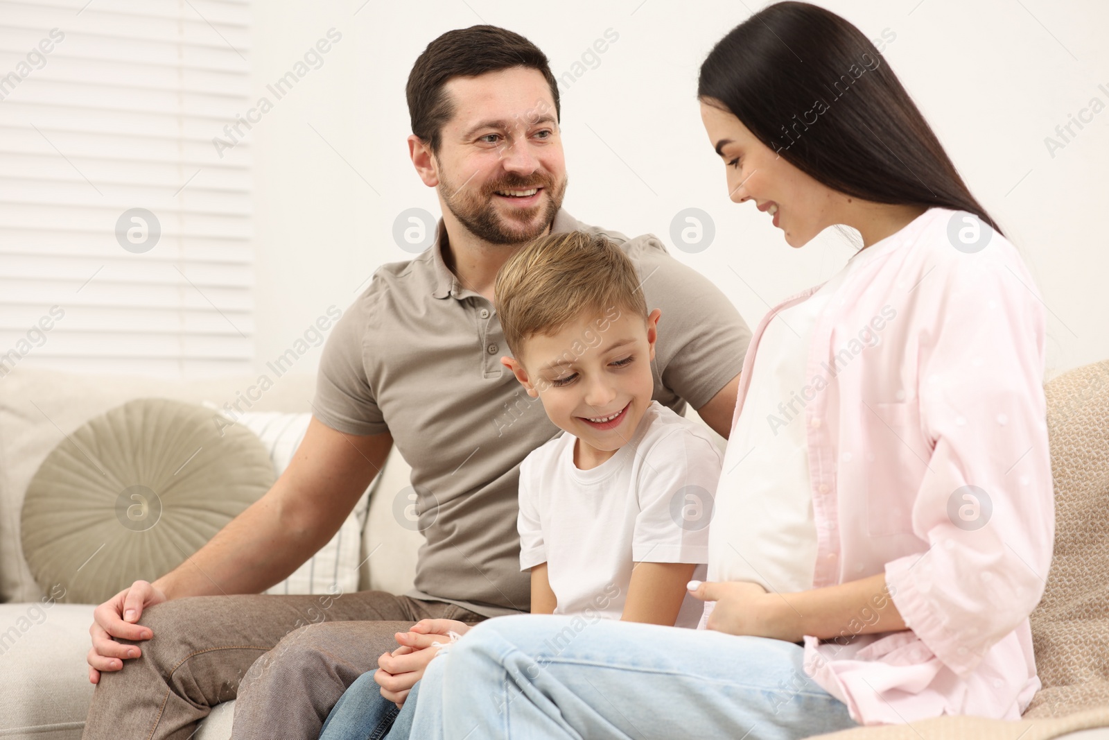 Photo of Happy pregnant woman spending time with her son and husband at home