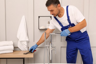 Professional plumber installing water tap in bathroom