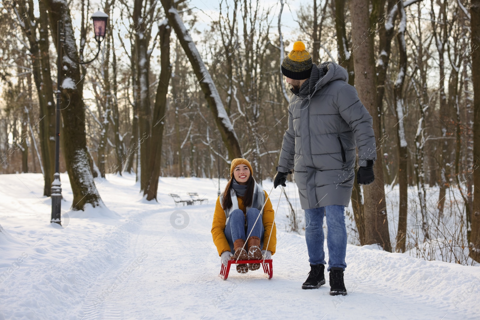 Photo of Man pulling his girlfriend in sleigh outdoors on winter day