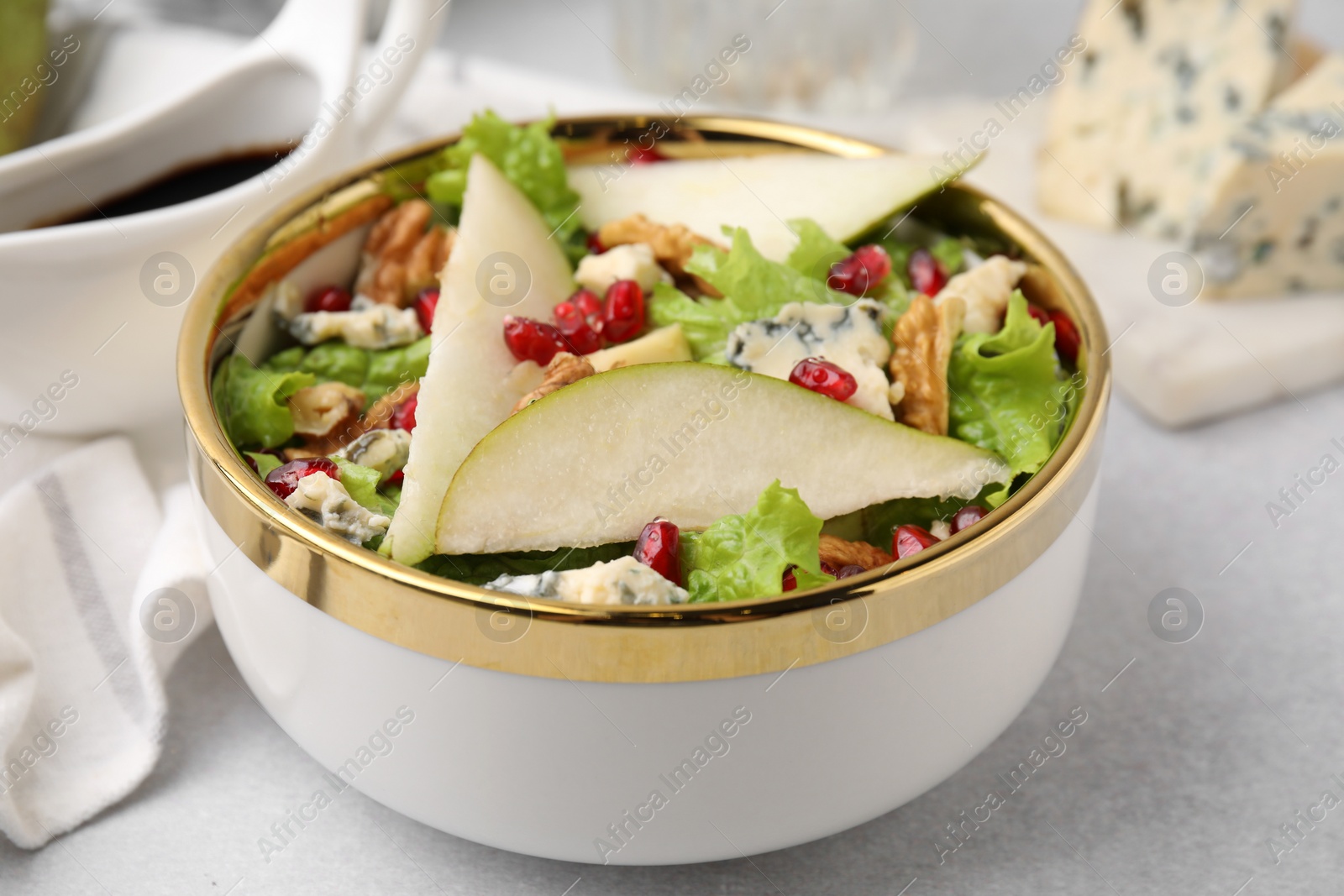 Photo of Delicious pear salad in bowl on light table, closeup