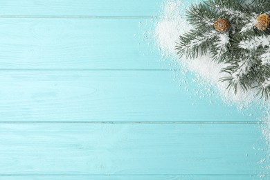 Top view of fir branches and snow on light blue wooden background, space for text. Winter holidays