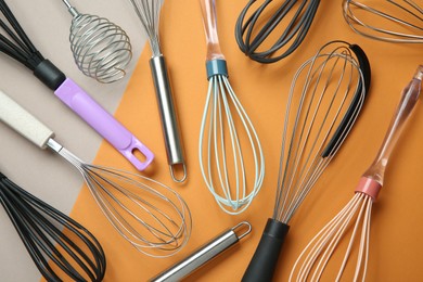 Different whisks on color background, flat lay