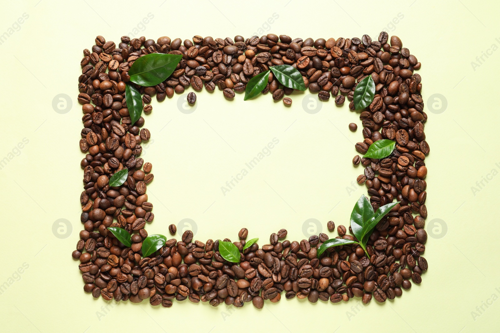 Photo of Frame made of fresh green coffee leaves and beans on light green background, top view. Space for text