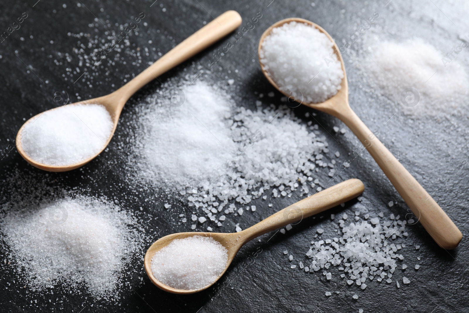 Photo of Organic salt in spoons on black table