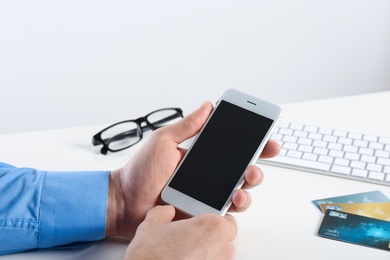 Man using mobile phone at table, closeup with space for design