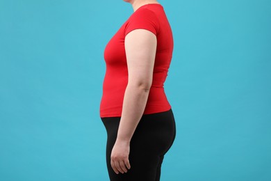 Photo of Overweight woman on light blue background, closeup