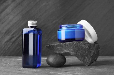 Photo of Cosmetic products and stones on grey background