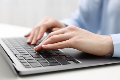 E-learning. Woman using laptop at white table indoors, closeup