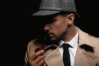 Photo of Old fashioned detective with smoking pipe on dark background, closeup