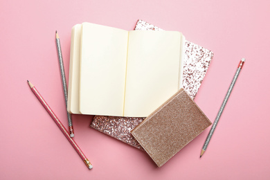 Photo of Stylish notebooks and pens on pink background, flat lay