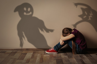 Image of Scared little girl suffering from sciophobia and phantoms behind her. Irrational fear of shadows