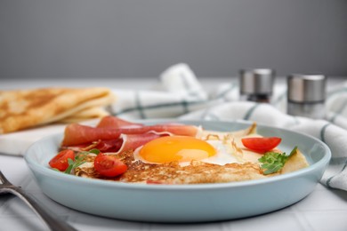 Delicious crepe with egg served on white table, closeup. Breton galette