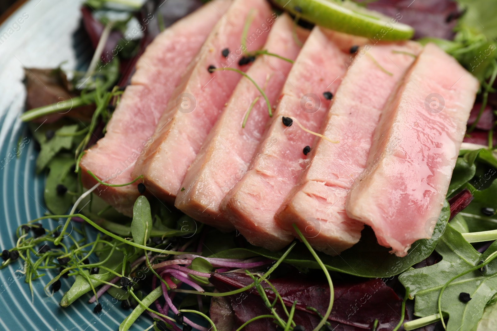 Photo of Pieces of delicious tuna steak with salad on plate, closeup