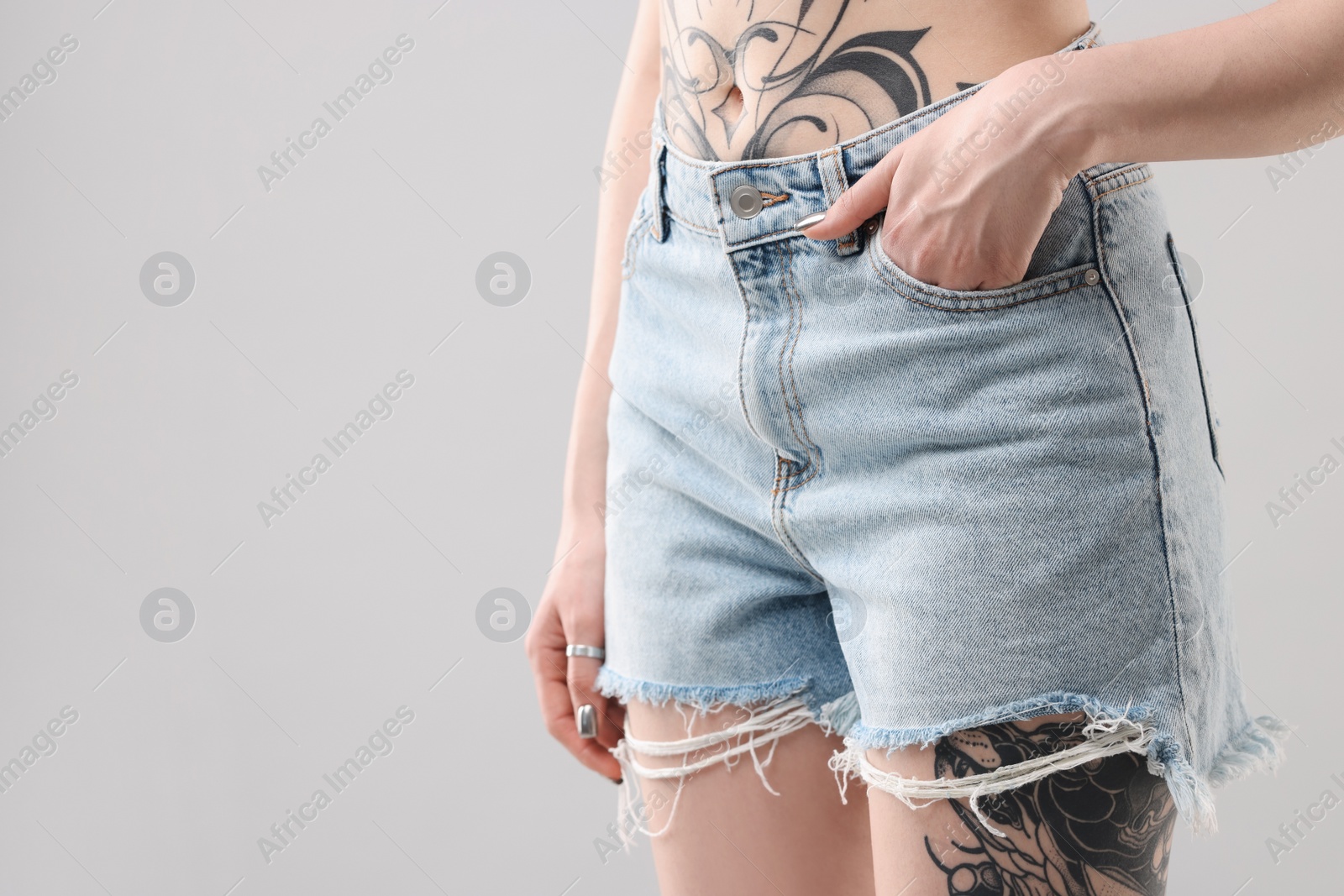 Photo of Woman with cool tattoos on grey background, closeup. Space for text