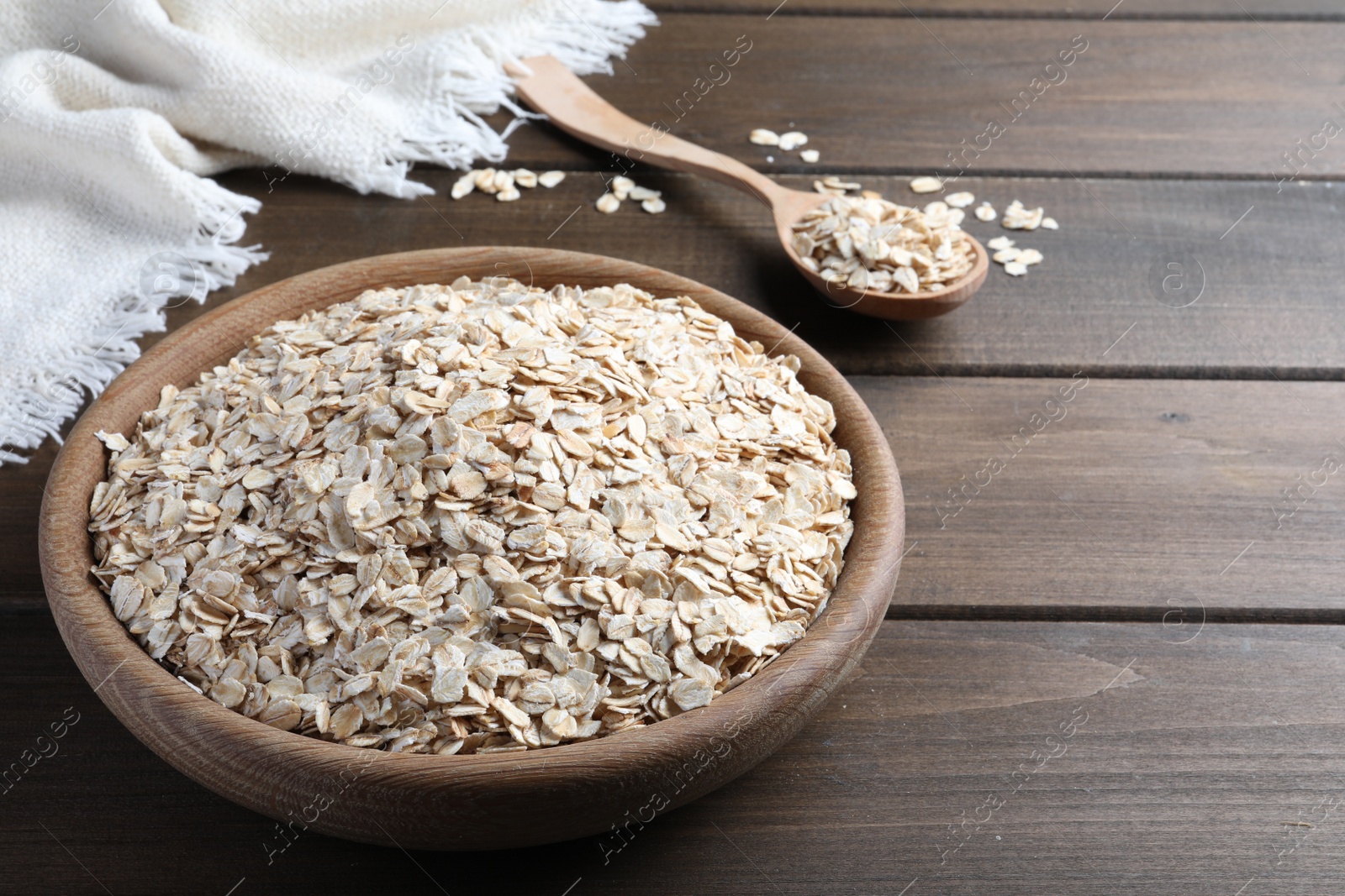 Photo of Bowl and spoon with oatmeal on wooden table. Space for text