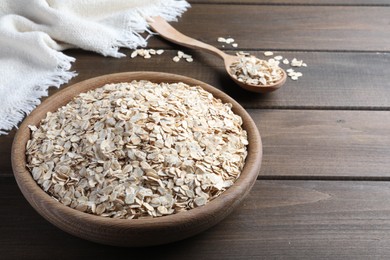 Photo of Bowl and spoon with oatmeal on wooden table. Space for text