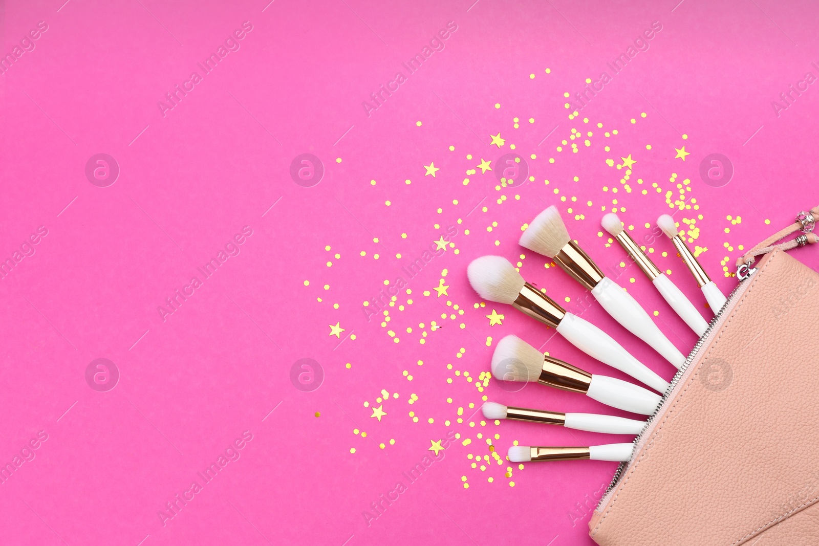 Photo of Different makeup brushes, case and shiny confetti on pink background, flat lay. Space for text