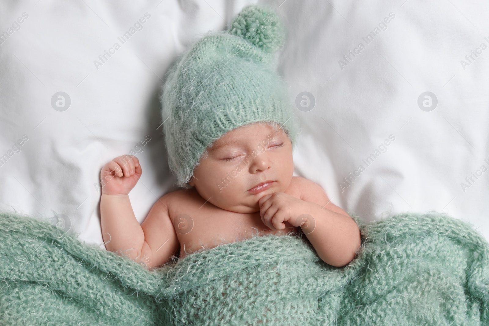 Photo of Cute little baby sleeping under knitted plaid in bed, top view