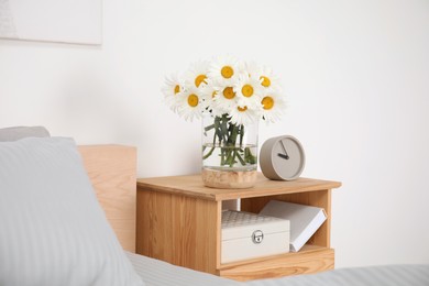 Photo of Bouquet of beautiful daisy flowers on wooden nightstand in bedroom