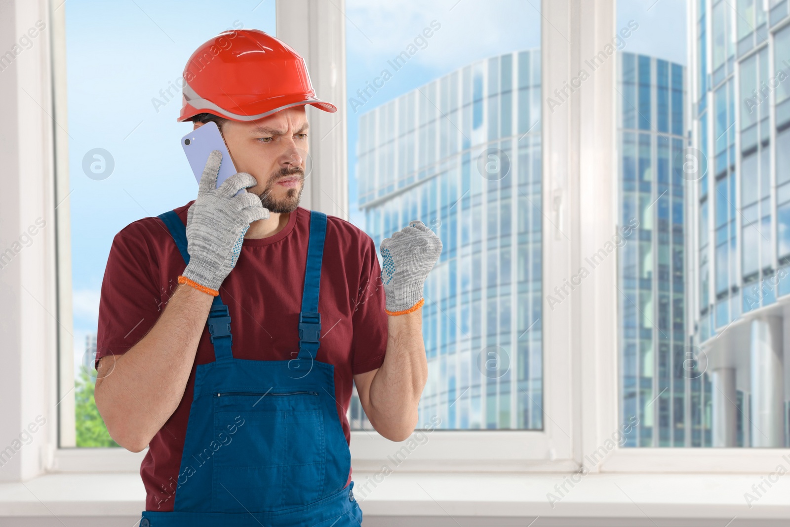 Photo of Professional repairman in uniform talking on phone indoors, space for text