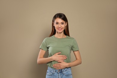 Photo of Healthy woman holding hands on belly against beige background