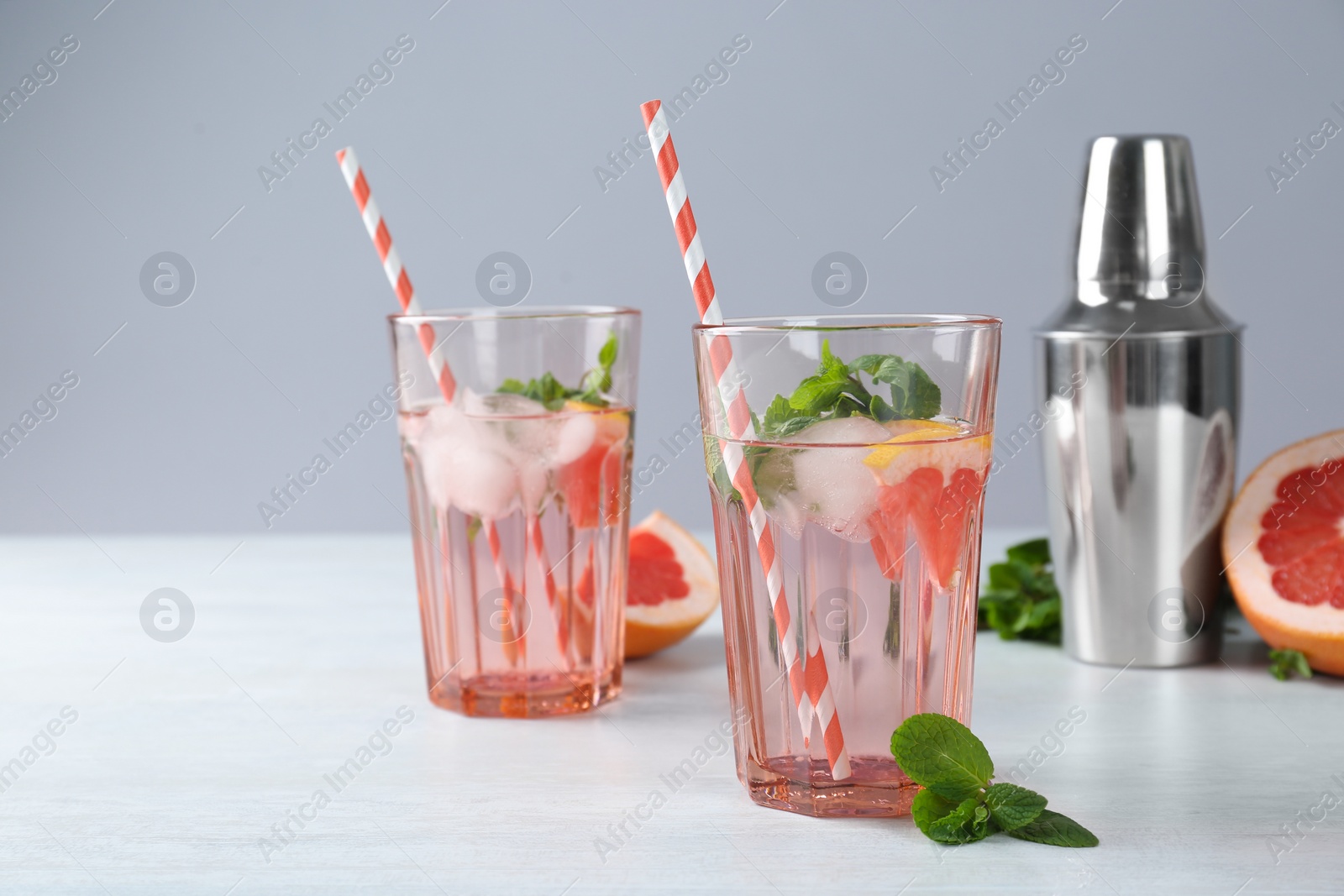 Photo of Delicious cocktails with grapefruit, mint and ice balls on white table, space for text