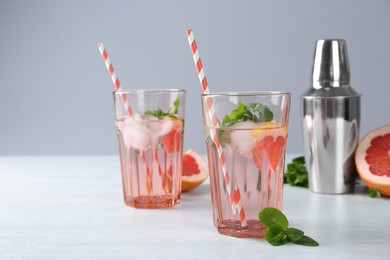 Photo of Delicious cocktails with grapefruit, mint and ice balls on white table, space for text