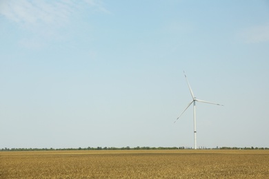 Photo of Modern wind turbine in field on sunny day. Energy efficiency