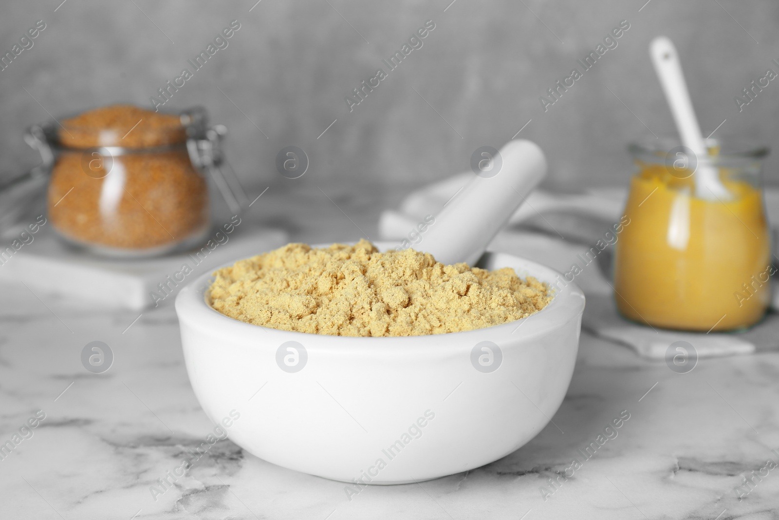 Photo of Mortar with aromatic mustard powder on white marble table